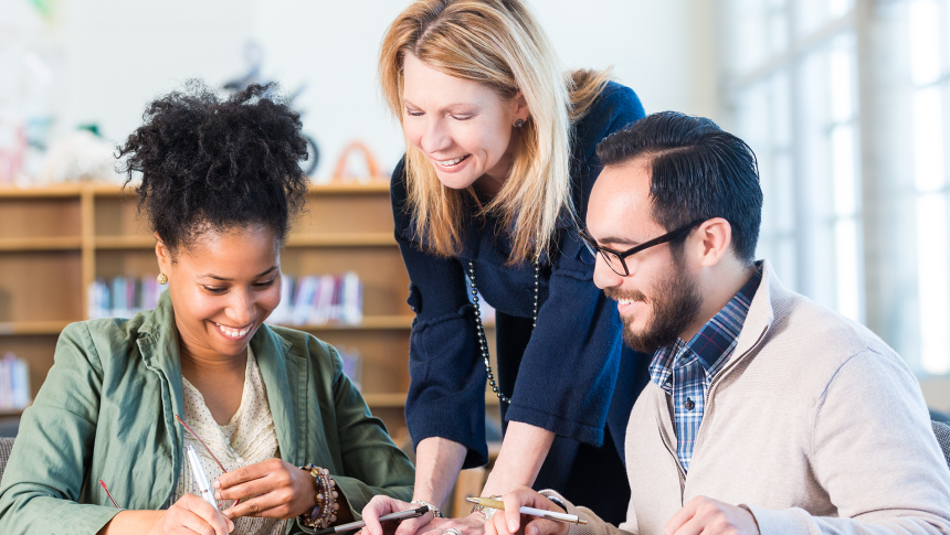 Three smiling educators, 2 women and 1 man, reading and sharing notes