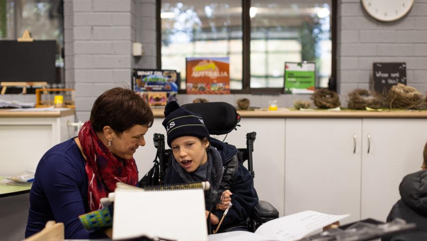 Teacher sitting with student in wheelchair