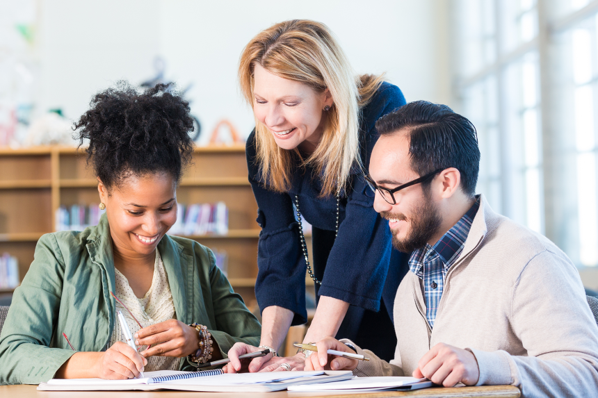 Three smiling educators, 2 women and 1 man, reading and sharing notes